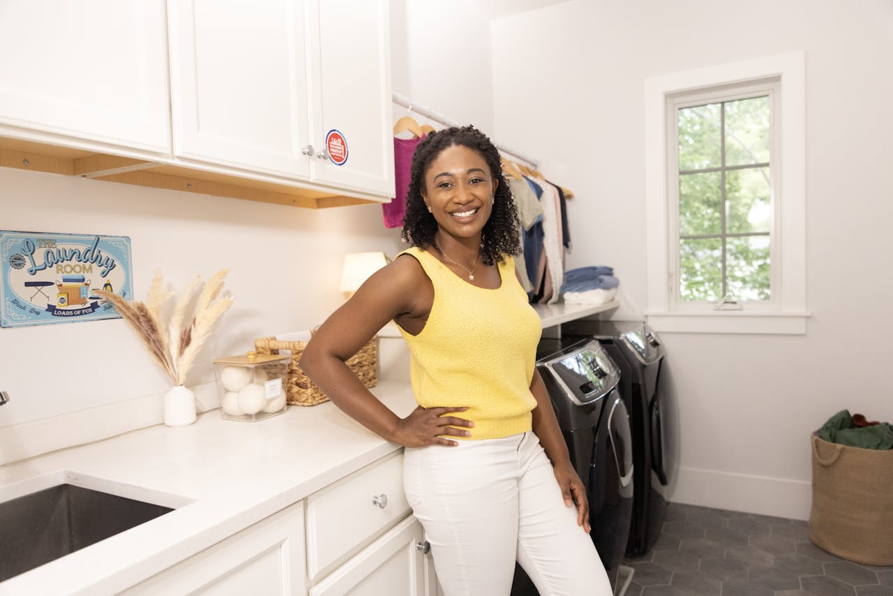 Smiling woman in laundry room with modern decor and appliances, showcasing a happy and clean home environment.