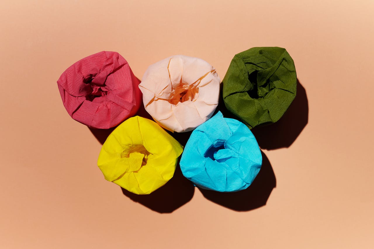 Brightly colored toilet paper rolls arranged in a creative still life setup.